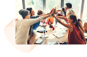 Team of employees engaging around a table and high fiving.