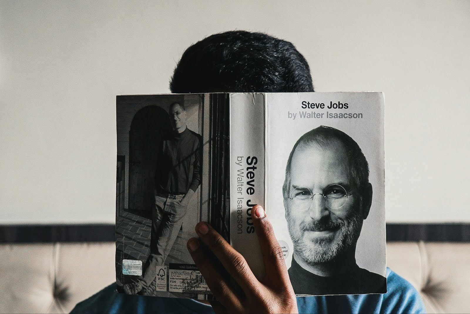 Person reading 'Steve Jobs' by Walter Isaacson, with the book cover featuring a portrait of the Apple founder. The image symbolizes innovation, leadership, and creativity, as highlighted on the WorkBuzz blog.