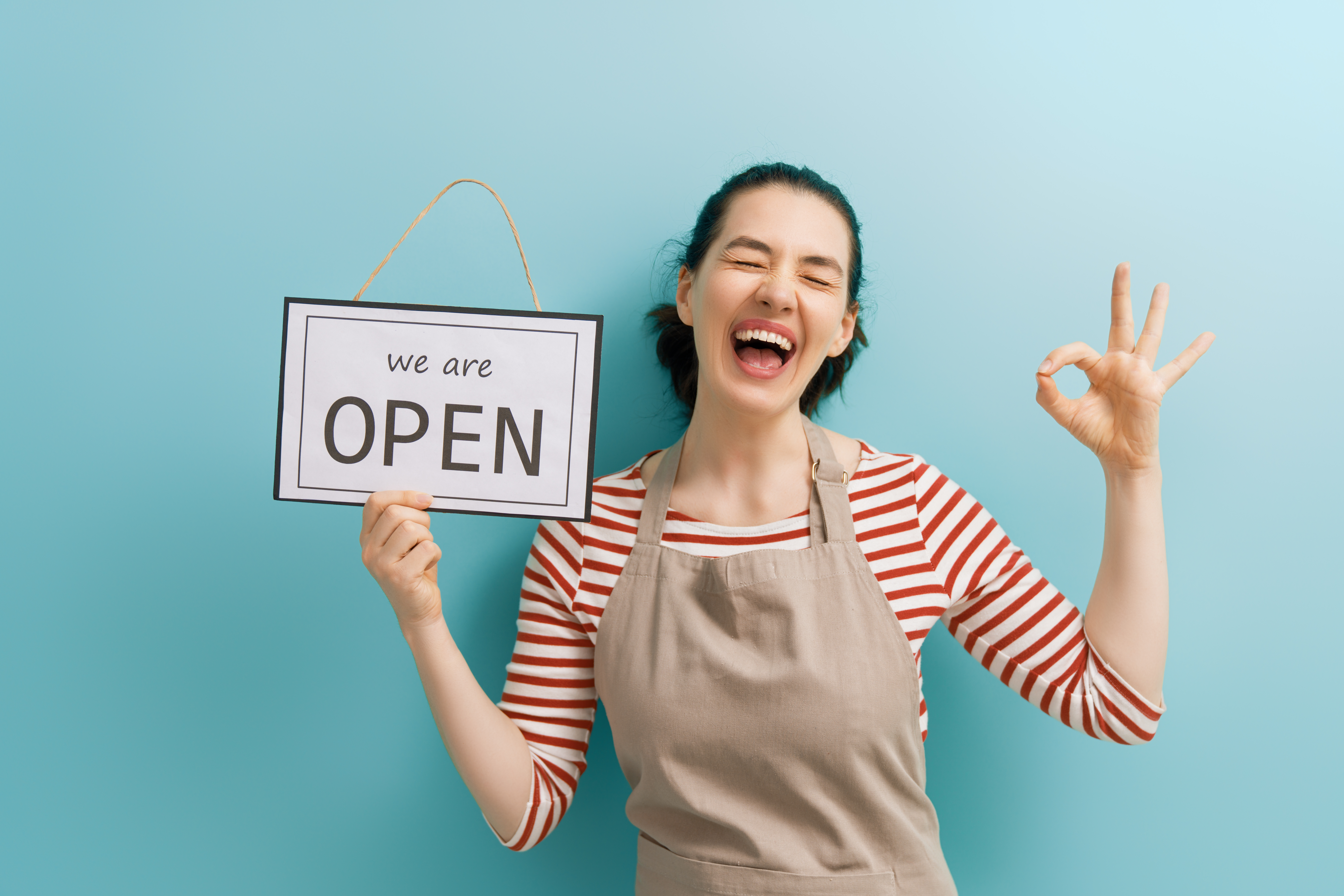 A photo of a woman holding a we are open sign